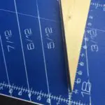 A blue cutting mat with a ruler and a triangle.